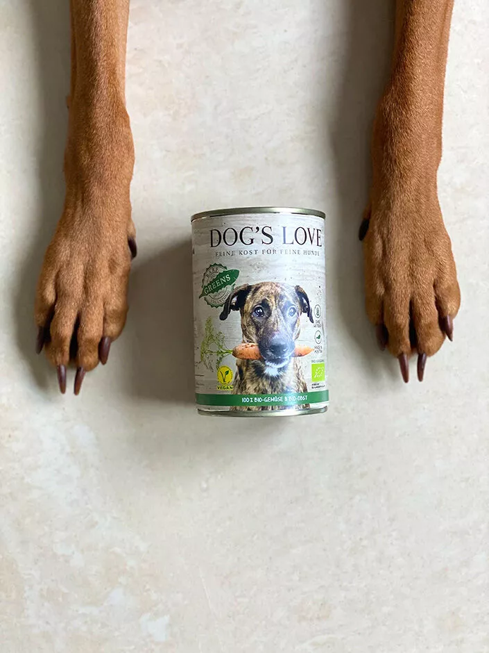 Hundepfoten neben einer Hundefutterdose von Dog's Love