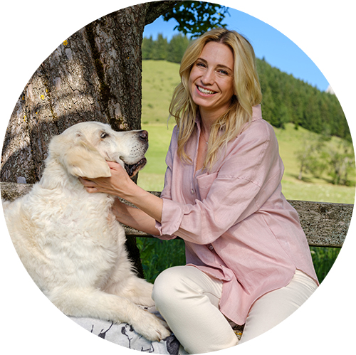 Katharina Miklauz sitzt mit ihrer Hündin Nala unter einem Baum auf einer Bank