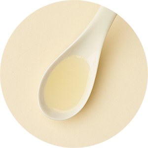 White spoon filled with oil on a beige background