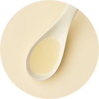 Cuillère blanche remplie d'huile sur fond beige
